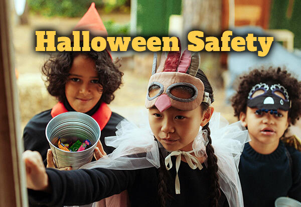 Three kids ringing door bell dressed in Halloween costumes